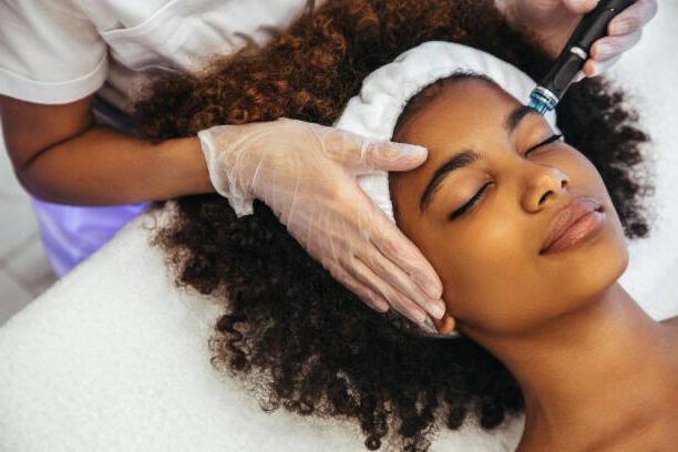Gerätegestützte Gesichtsbehandlung bei einer Kundin mit Haarband