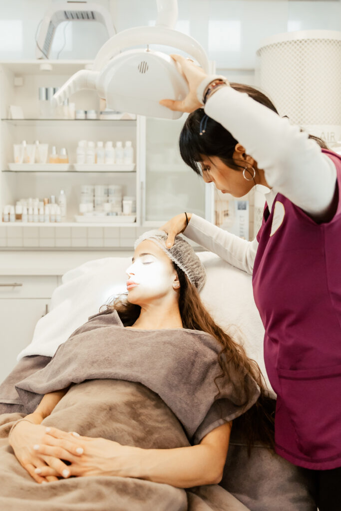 Kosmetikerin bei einer Gesichtsbehandlung mit Maske im Behandlungsraum